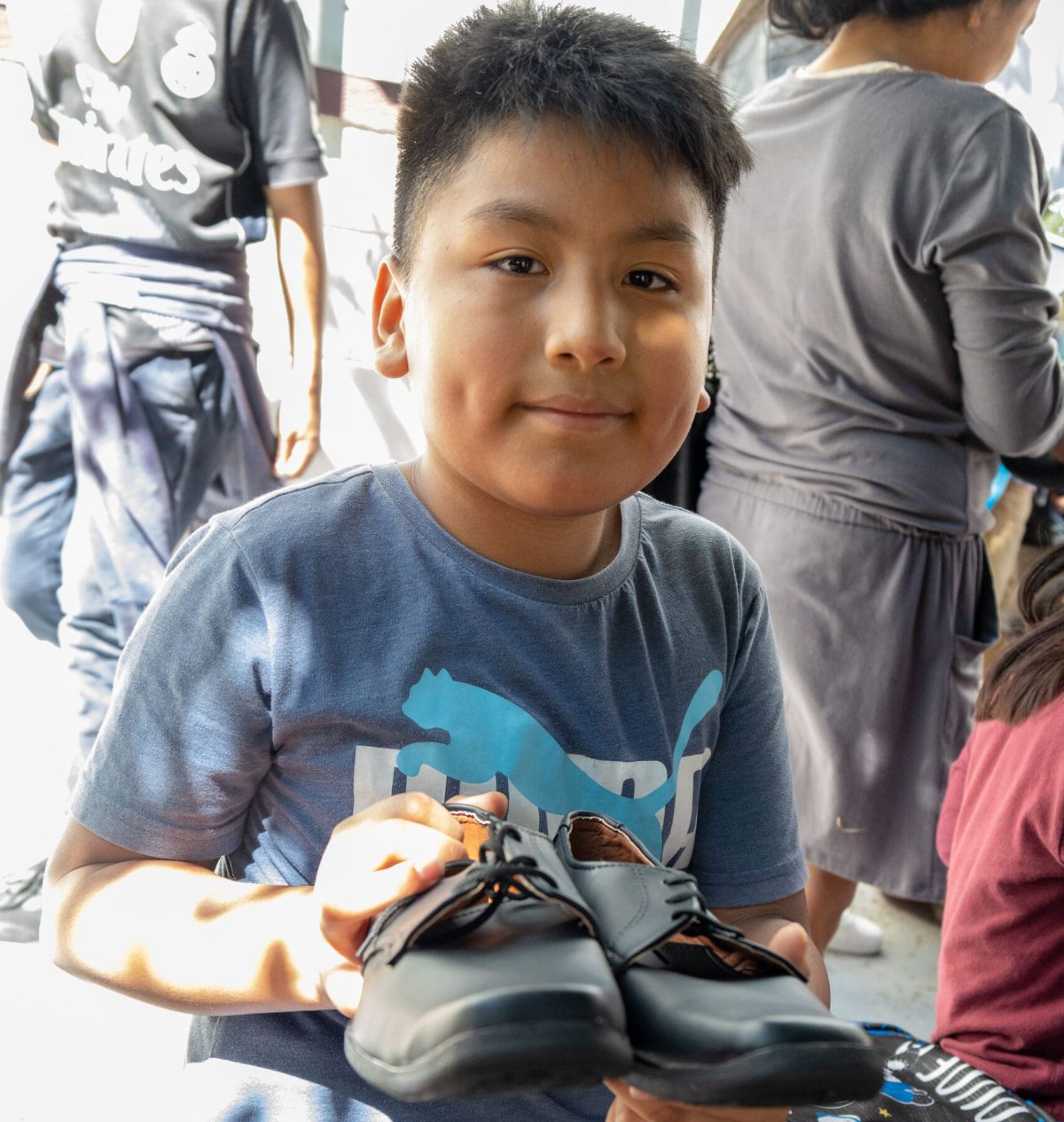 Boy smiling and holding a new pair of school shoes